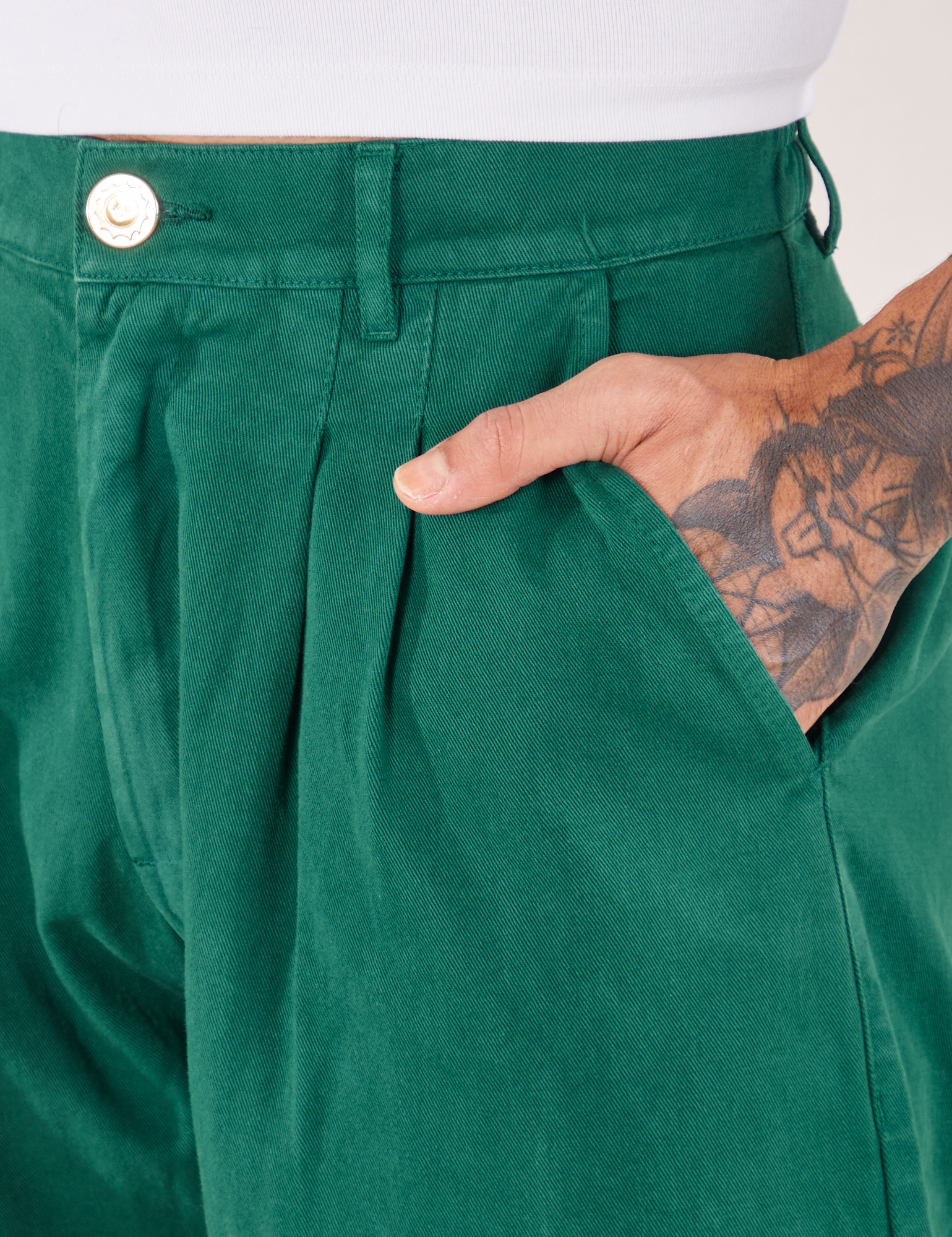 Front pocket close up of Heavyweight Trousers in Hunter Green. Jesse has their hand in the pocket.