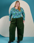 Juliet is wearing Long Sleeve Baby Tee in Angel Print tucked into evergreen Drop Pocket Cargo Pants