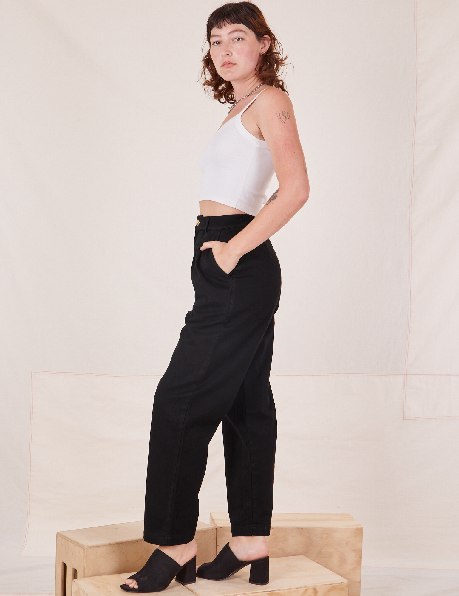 Side view of Organic Trousers in Basic Black and vintage off-white Cami worn by Alex