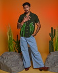 Jesse is wearing Paintstamped Pantry Button-Up in Cactus and light wash Indigo Wide Leg Trousers