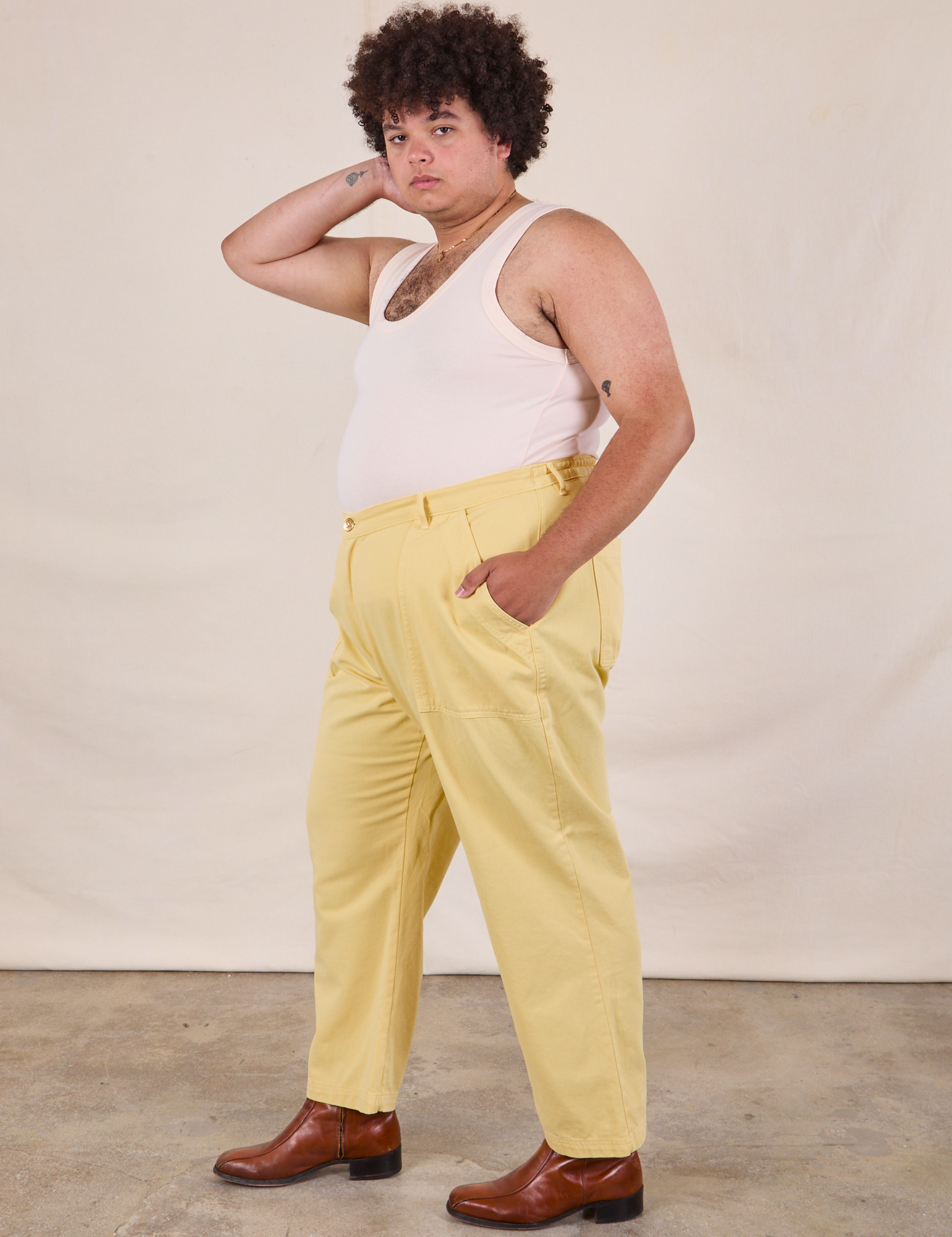 Side view of Work Pants in Butter Yellow and vintage tee off-white Tank Top on Miguel