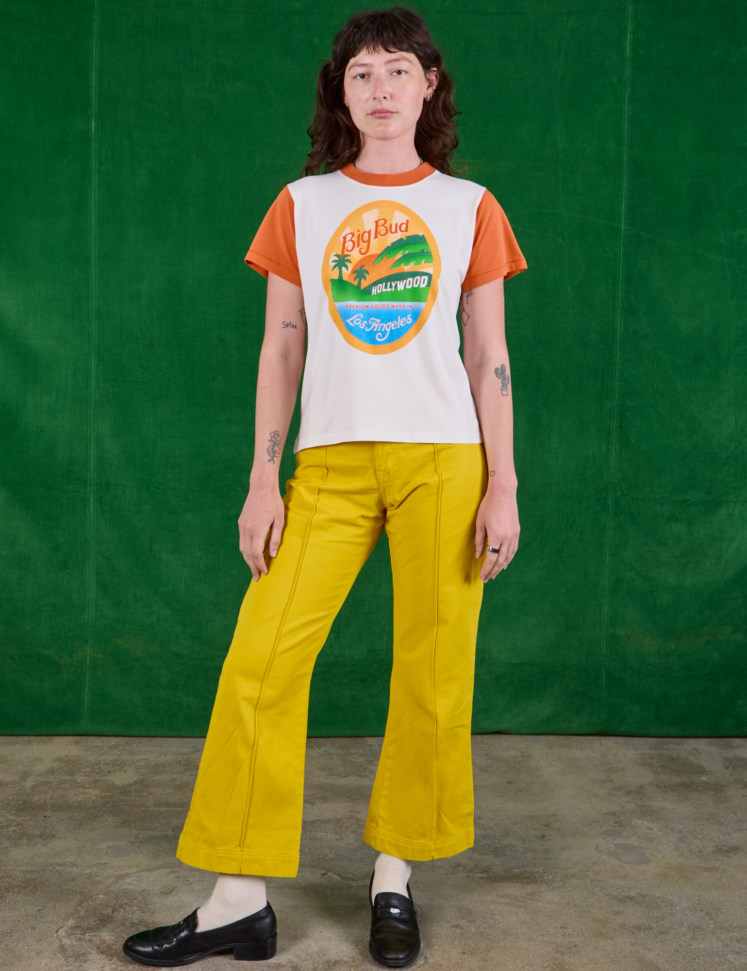 Alex is wearing Hollywood Tourist Tee and golden yellow Western Pants