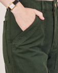 Petite Work Pants in Swamp Green front pocket close up. Hana has her hand in the pocket.