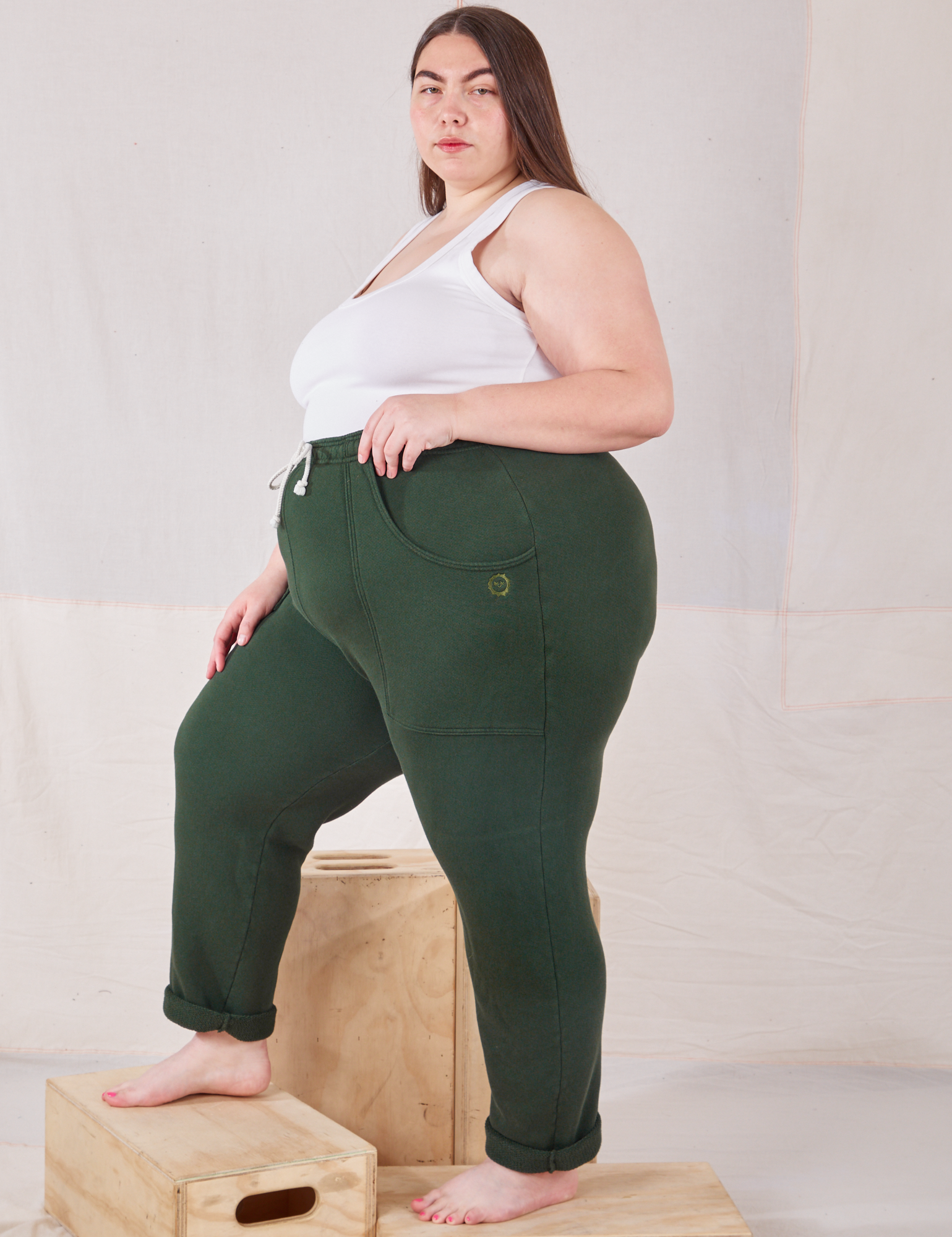 Side view of Rolled Cuff Sweat Pants in Swamp Green and vintage off-white Cropped Tank on Marielena
