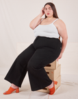 Marielena is wearing Bell Bottoms in Basic Black and Cropped Cami in vintage tee off-white. She is sitting on a stack of wooden crates.