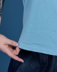 Sydney is holding the hem of Painted Burly Tee in Baby Blue