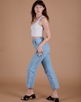 Side view of Carpenter Jeans in Light Wash and vintage tee white Cropped Tank