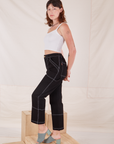 Side view of Carpenter Jeans in Black and Cropped Cami in vintage tee off-white on Alex