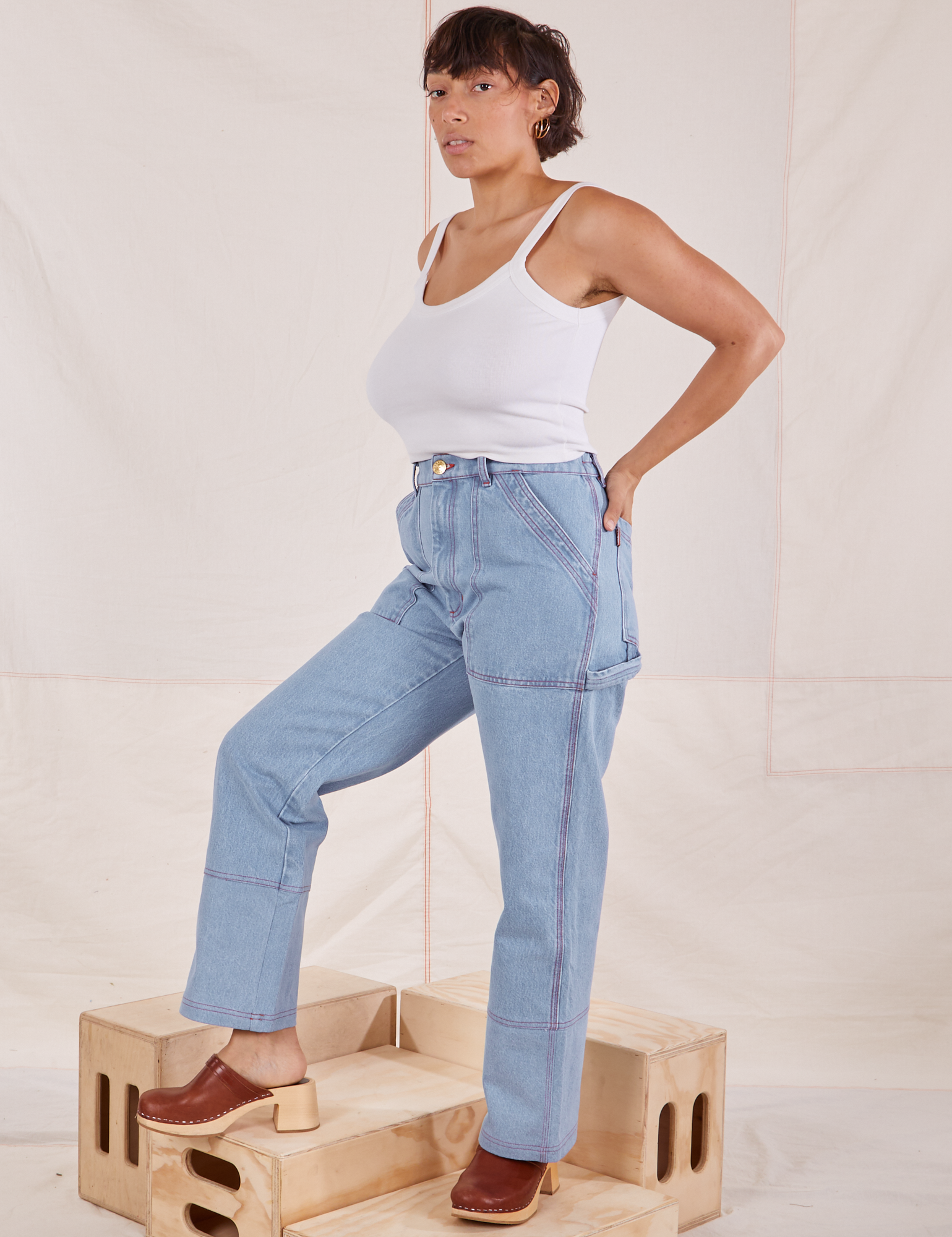Angled front view of Carpenter Jeans in Light Wash and Cropped Cami in vintage tee off-white worn by Tiara