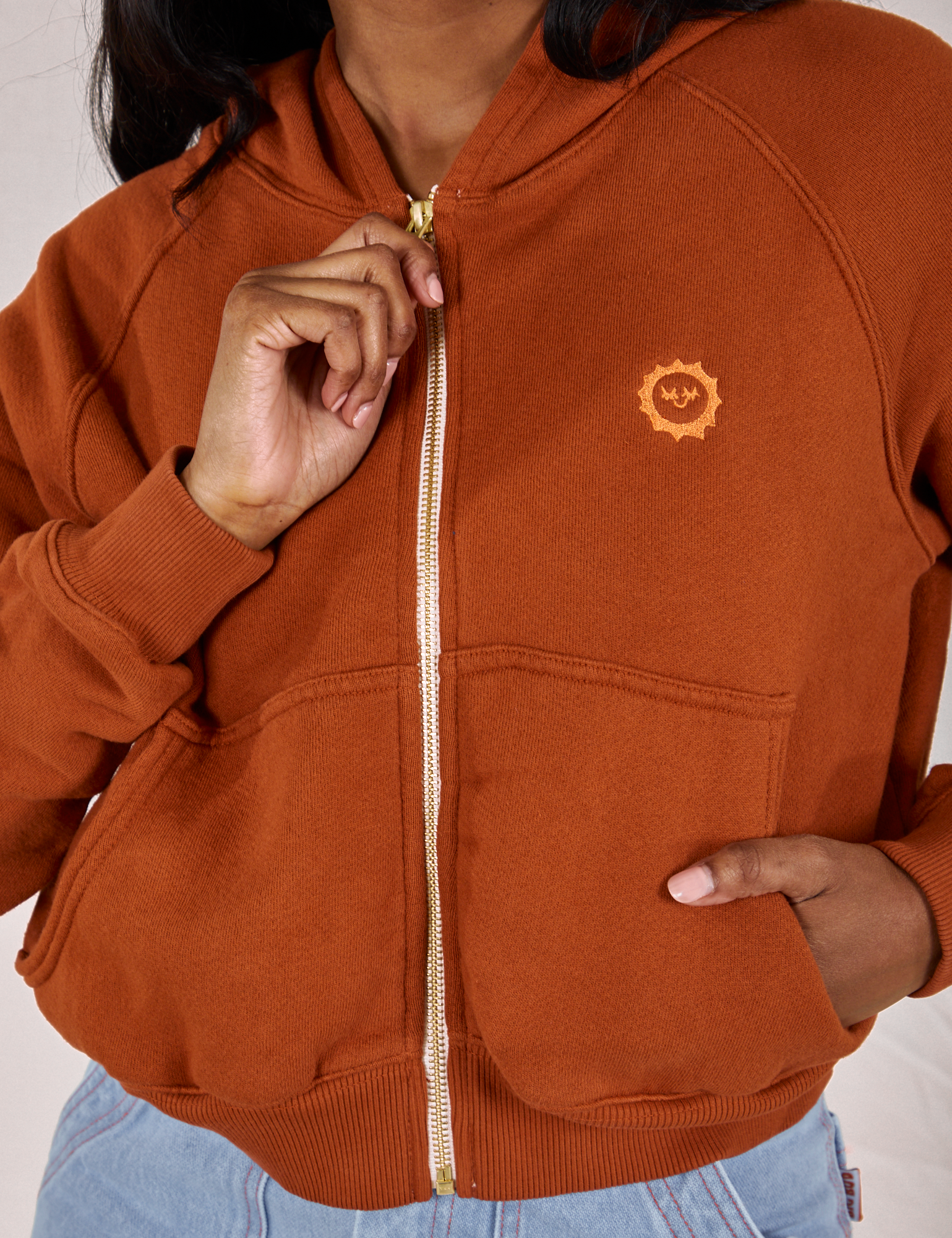 Kandia is wearing a zipped up Cropped Zip Hoodie in Burnt Terracotta