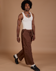Angled front view of Drop Pocket Cargo Pants in Fudgesicle Brown and Tank Top in vintage tee white on Jerrod