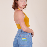 Side view of Halter Top in Mustard Yellow and light wash Frontier Jeans worn by Alex