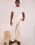 Issac 5’10” is and wearing M Heritage Trousers in Natural paired with Organic Vintage Tee in vintage tee off-white