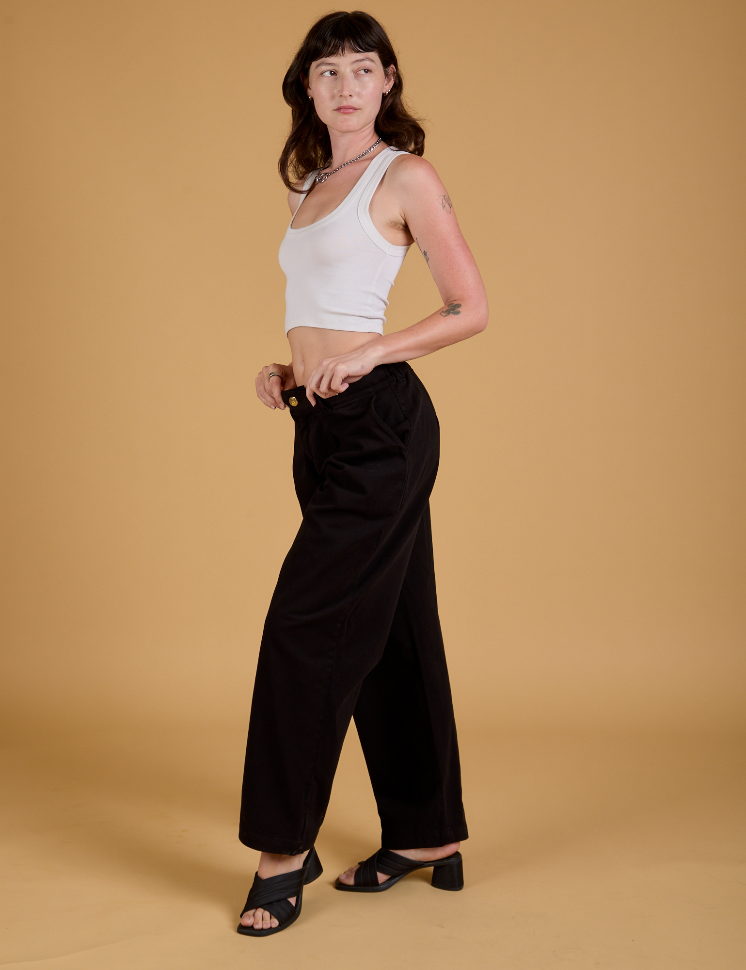 Alex is wearing Baggy Mid-Rise Trousers in Basic Black and vintage tee white Cropped Tank
