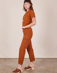 Side view of Short Sleeve Jumpsuit in Burnt Terracotta worn by Alex