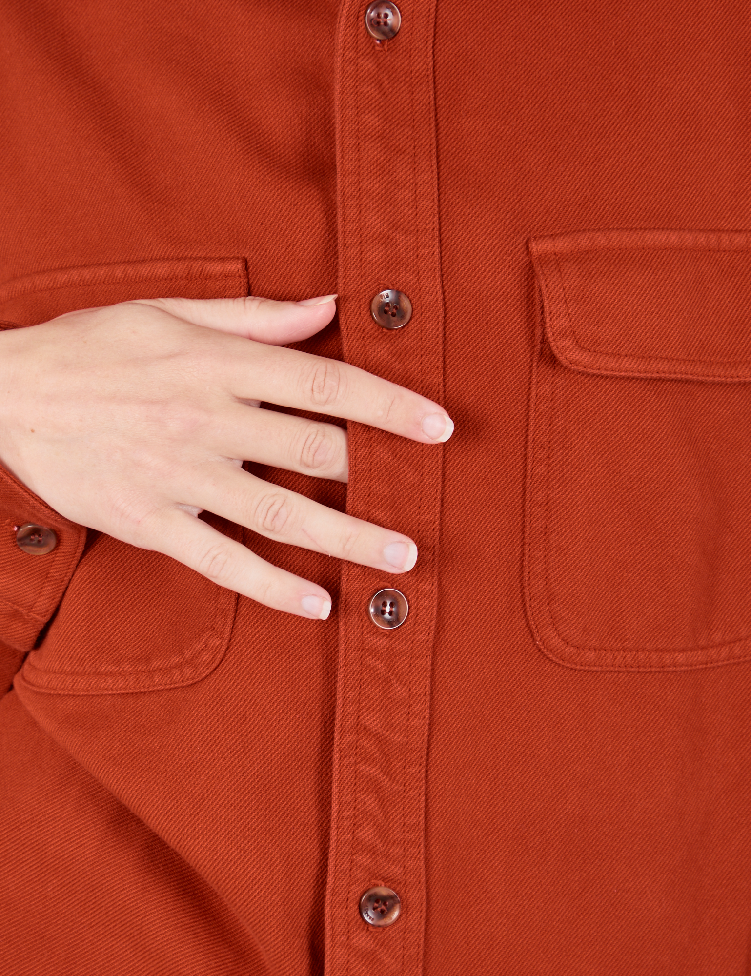 Flannel Overshirt in Paprika button placket close up. Alex has her hand resting on the front.