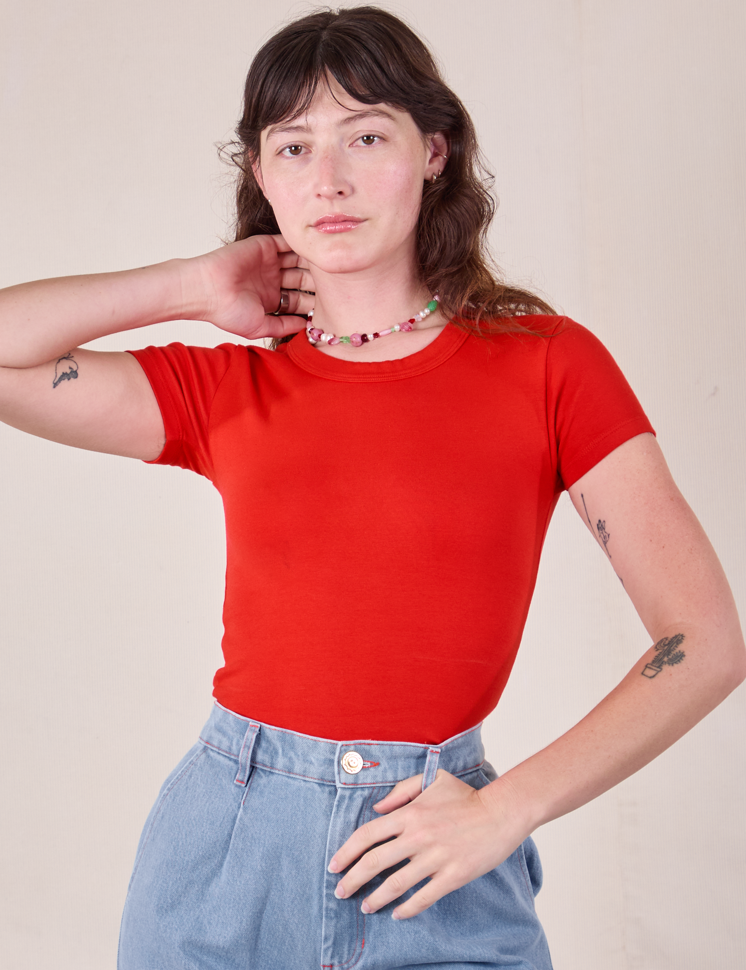 Alex is wearing Baby Tee in Mustang Red tucked into light wash Trouser Jeans
