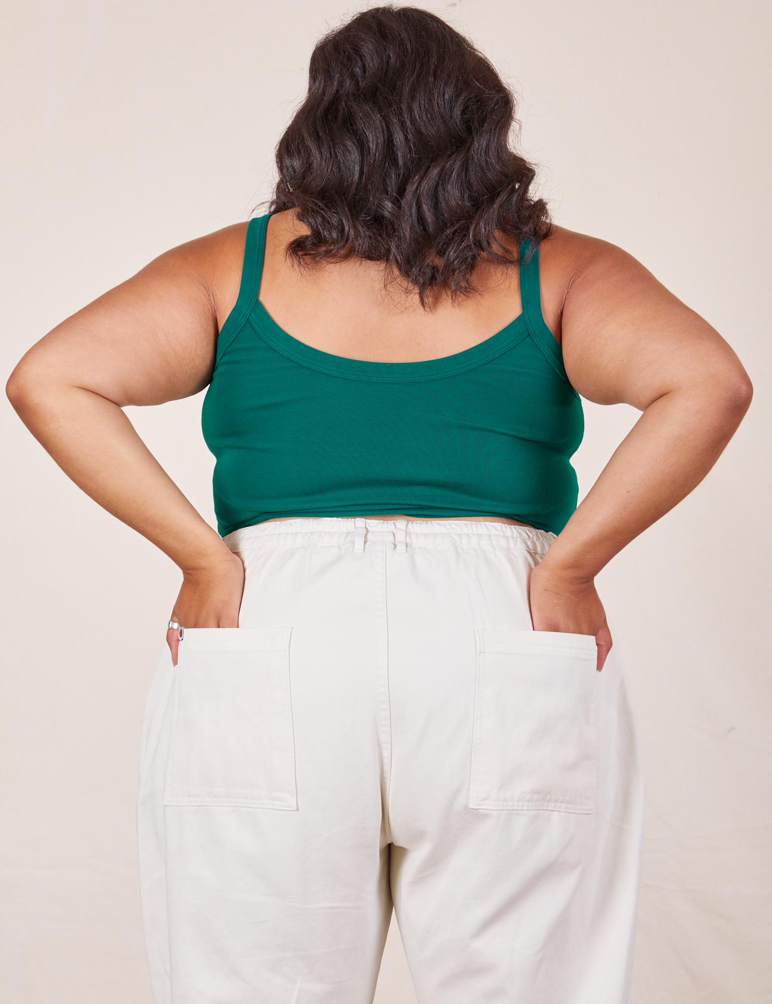 Back view of Cropped Cami in Hunter Green and vintage tee off-white Western Pants worn by Alicia. She has both hands in the back pant pockets.