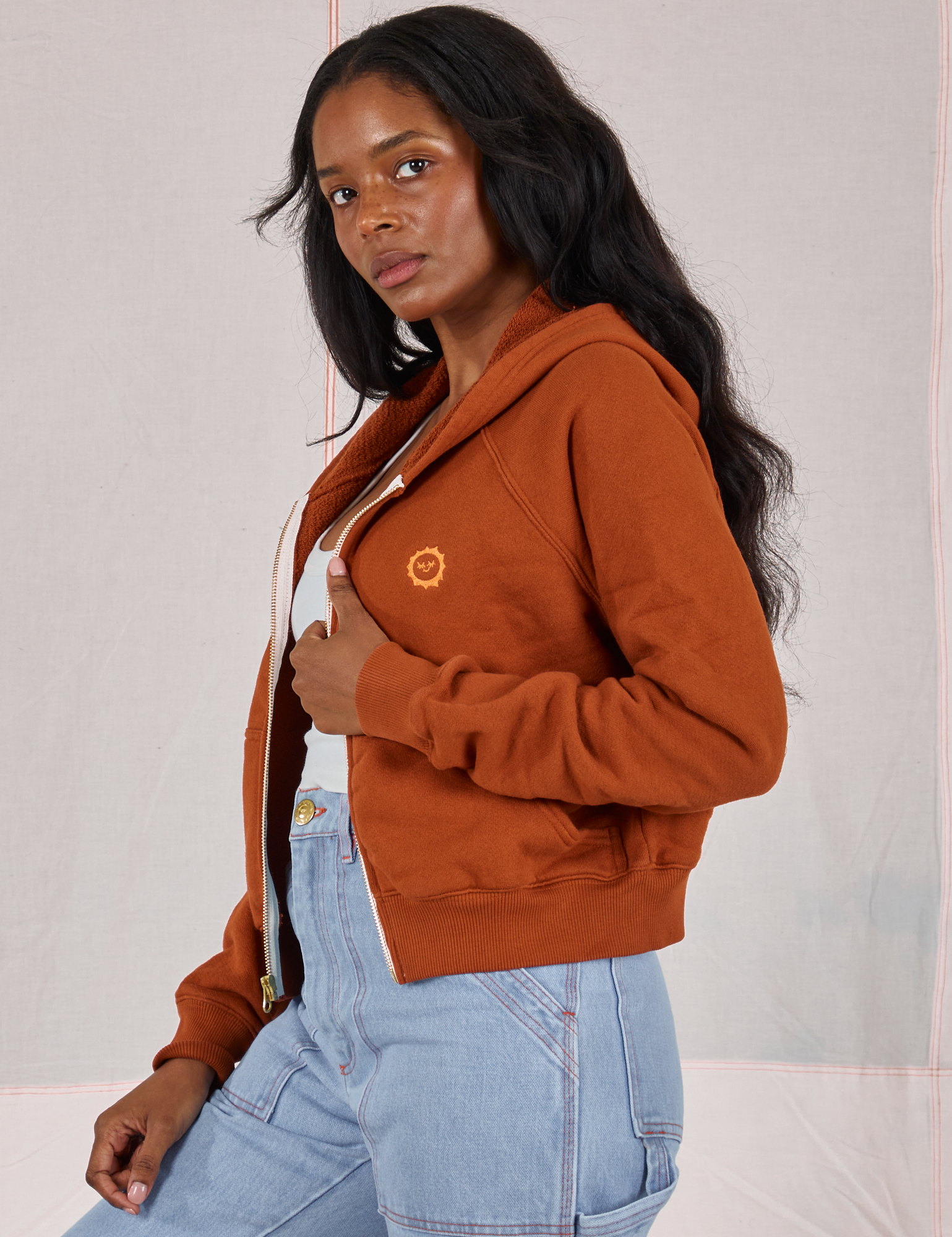 Side view of Cropped Zip Hoodie in Burnt Terracotta and light wash Carpenter Jeans on Kandia