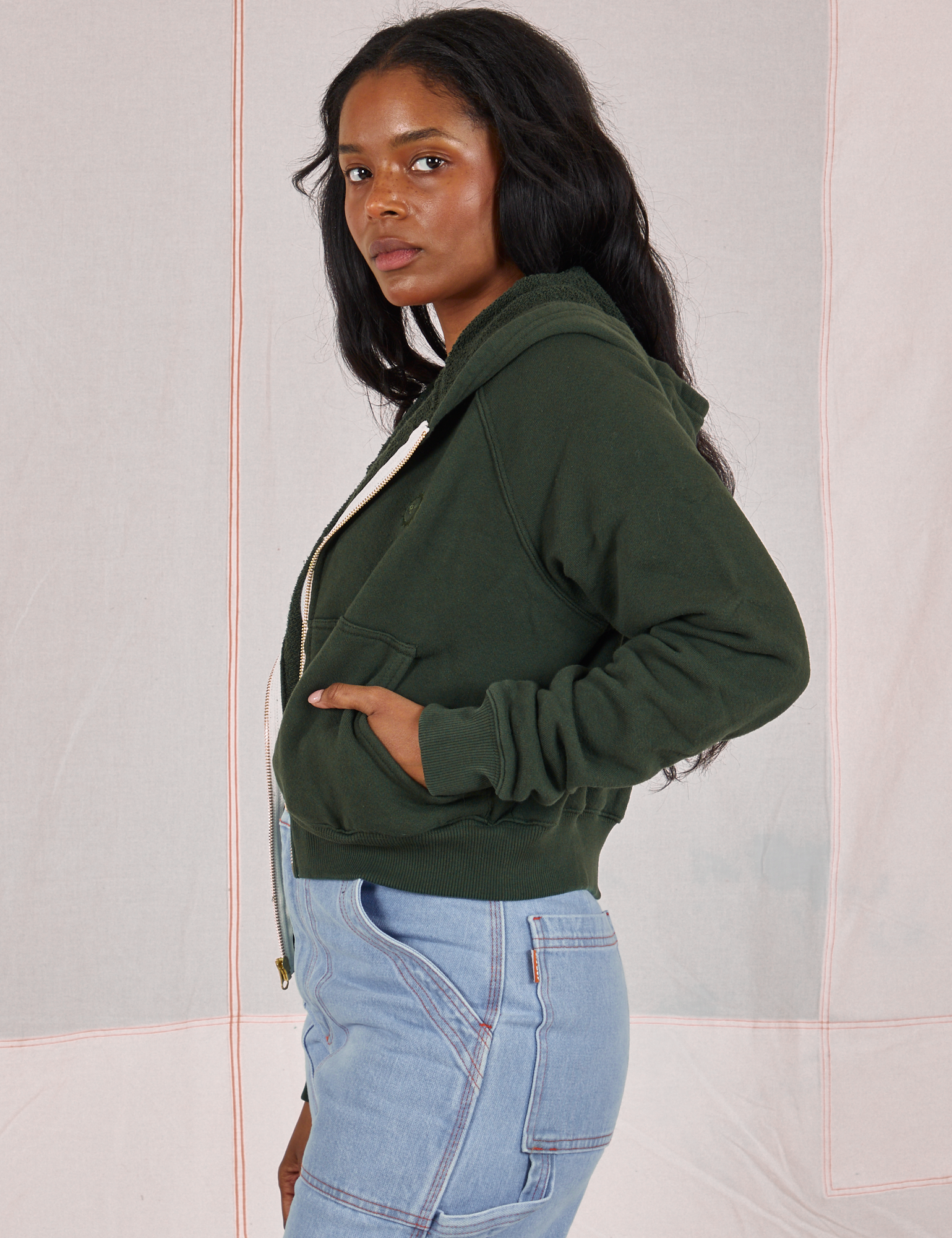 Side view of Cropped Zip Hoodie in Swamp Green and light wash Carpenter Jeans on Kandia