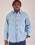Issac is wearing a buttoned up Denim Overshirt in Light Wash