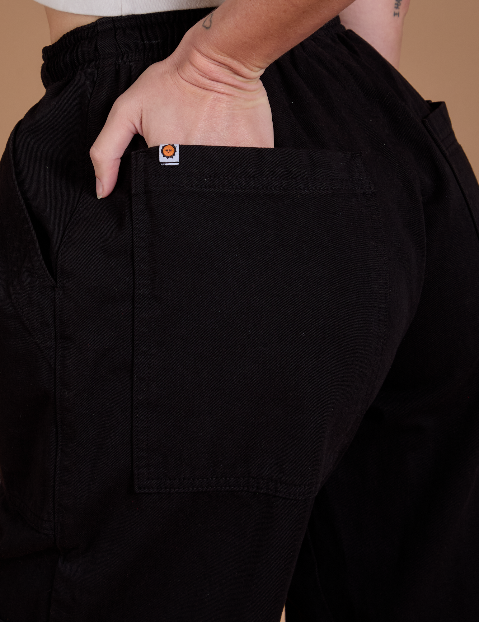 Close up of Alex's hand in the back pocket of Drop Pocket Cargo Pants in Basic Black