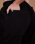 Close up of Alex's hand in the back pocket of Drop Pocket Cargo Pants in Basic Black