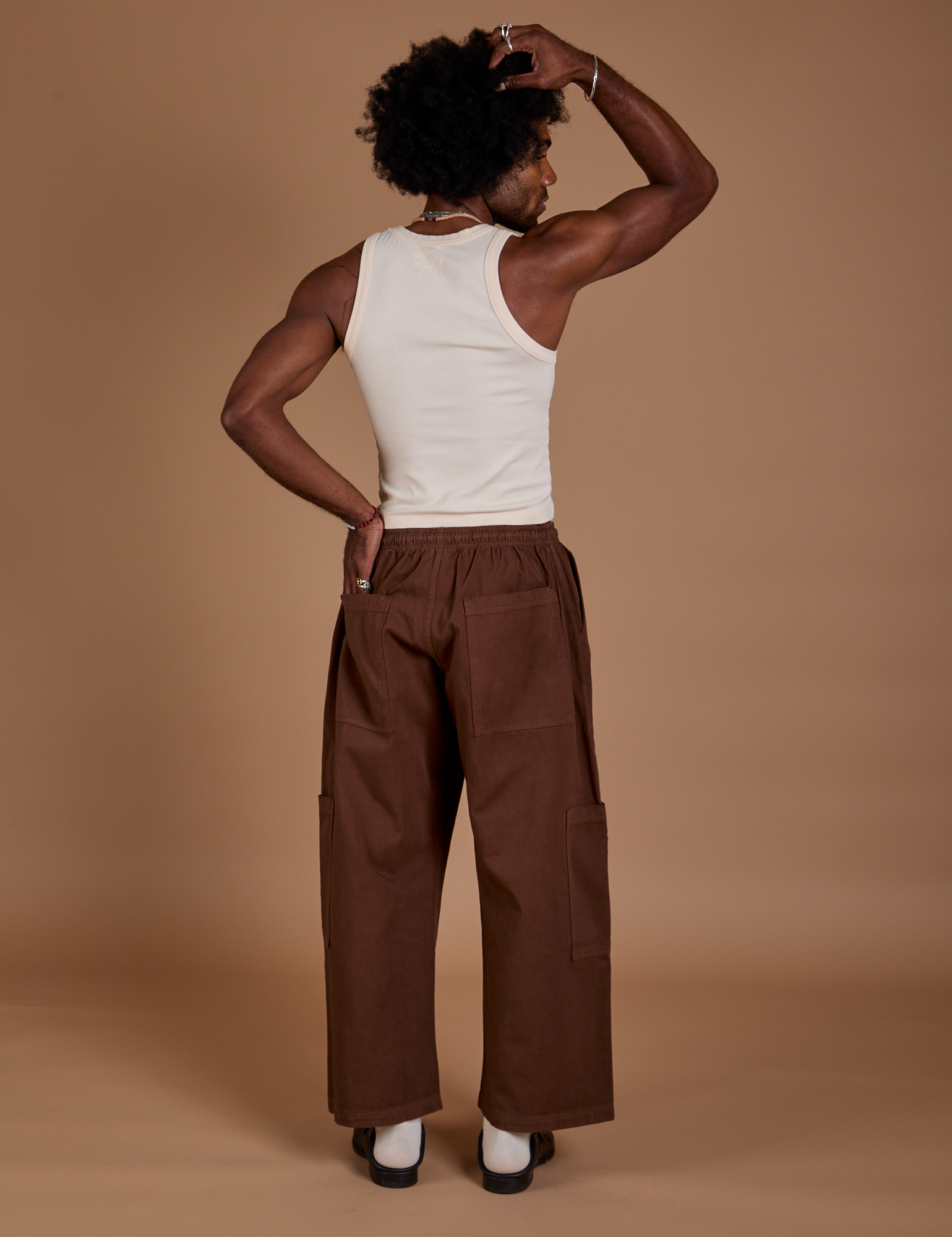 Back view of Drop Pocket Cargo Pants in Fudgesicle Brown and Tank Top in vintage tee white on Jerrod