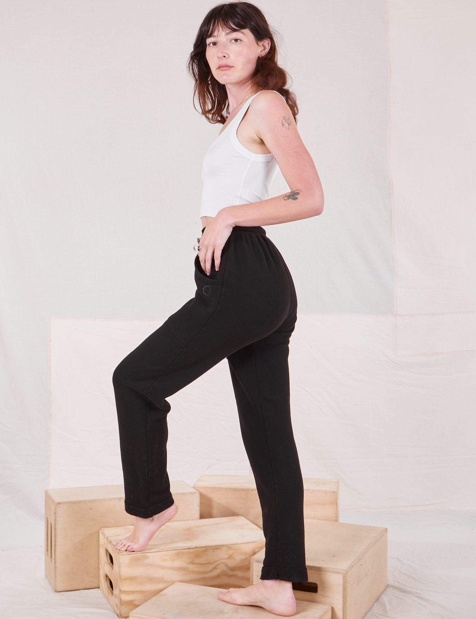 Side view of Rolled Cuff Sweat Pants in Basic Black and vintage off-white Cropped Tank on Alex