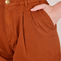Front pocket close up of Heavyweight Trousers in Burnt Terracotta. Alex has her hand in the pocket.