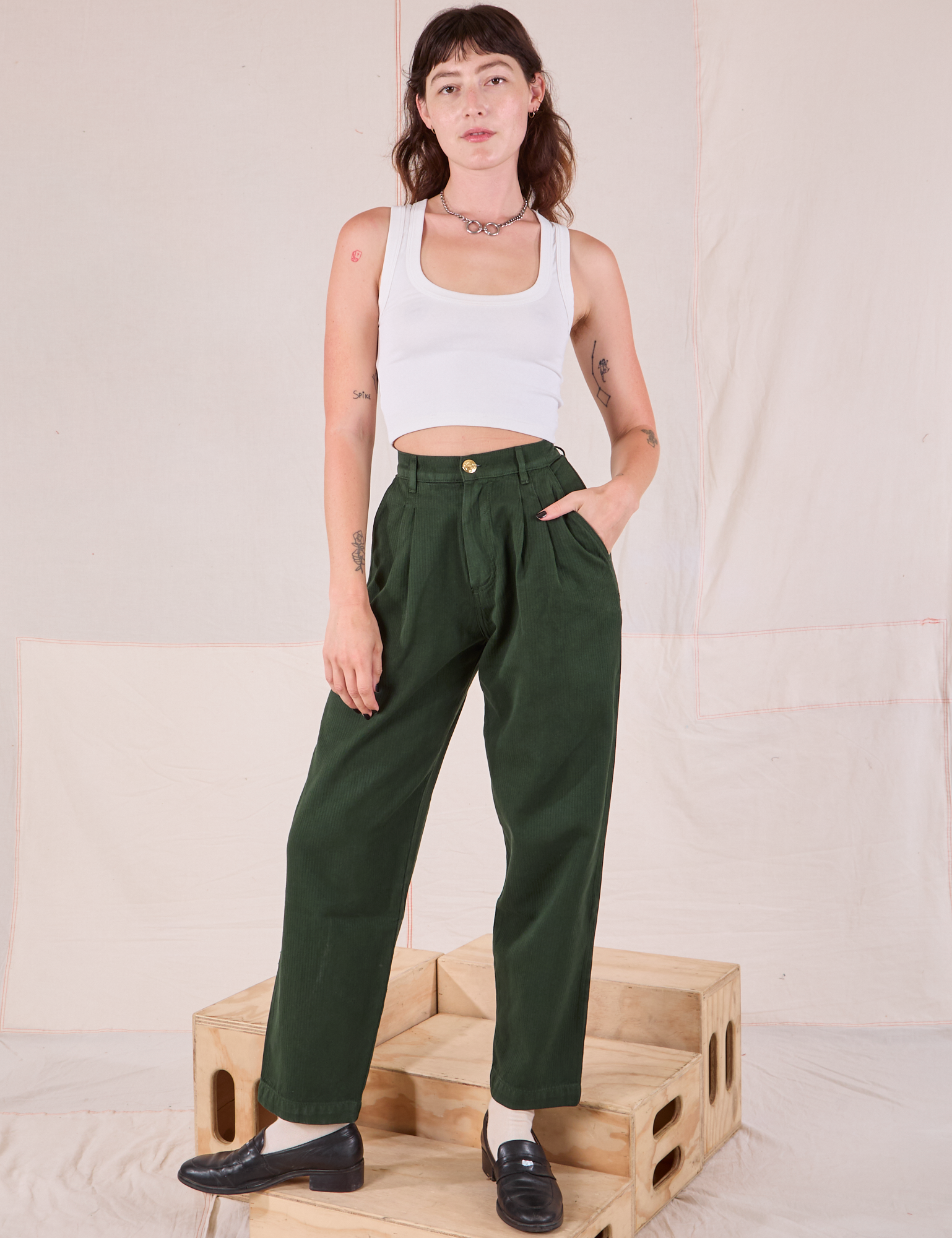 Alex is 5’8” and wearing XXS Heritage Trousers in Swamp Green paired with a Cropped Tank in vintage tee off-white