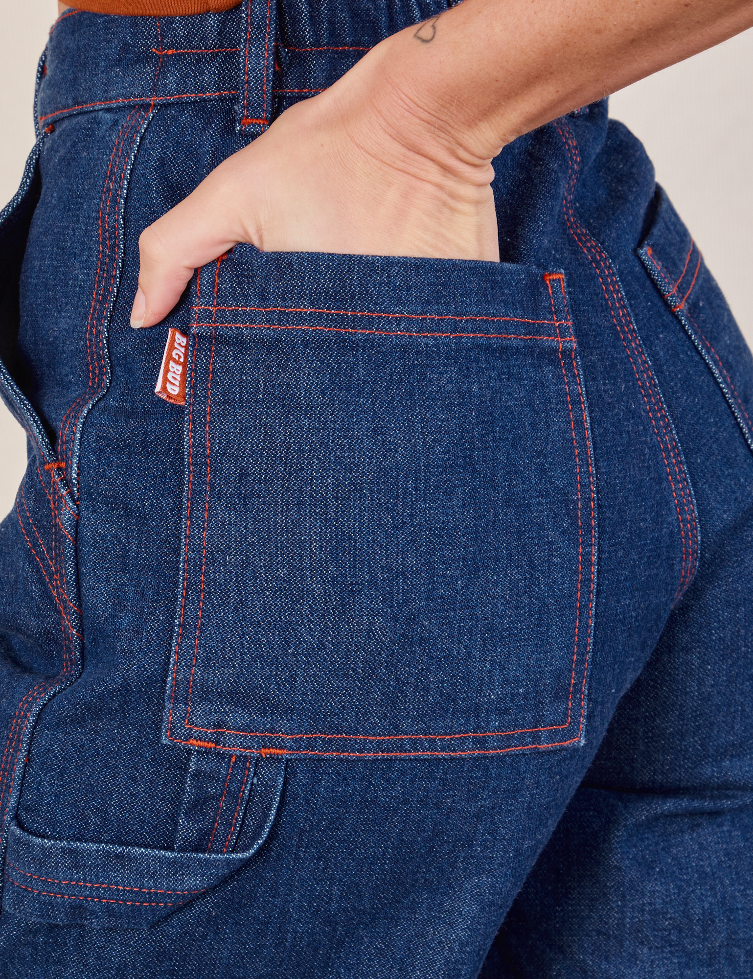 Carpenter Shorts in Dark Wash back pocket close up. Alex has her hand in the pocket.