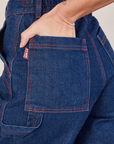 Carpenter Shorts in Dark Wash back pocket close up. Alex has her hand in the pocket.