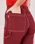 Railroad Carpenter Jeans in Mustang Red back close up. Alex has her hand in the pocket