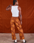 Back view of Paintstamped Work Pants in Orange and Cropped Tank in vintage tee off-white on Jerrod
