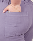 Back pocket close up of Short Sleeve Jumpsuit in Faded Grape. Ashley has her hand in the pocket.