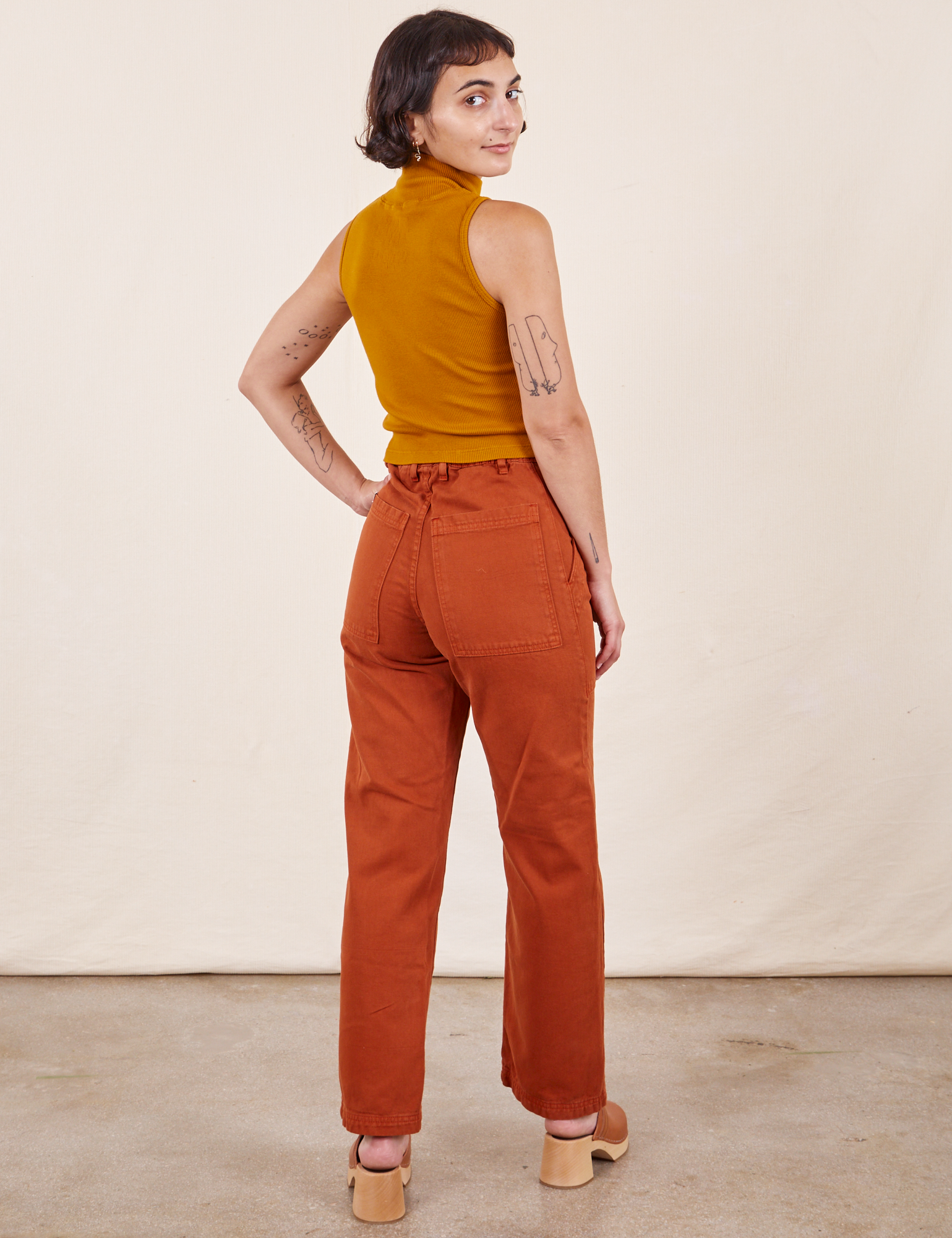 Work Pants in Burnt Terracotta back view on Soraya wearing spicy mustard Sleeveless Essential Turtleneck