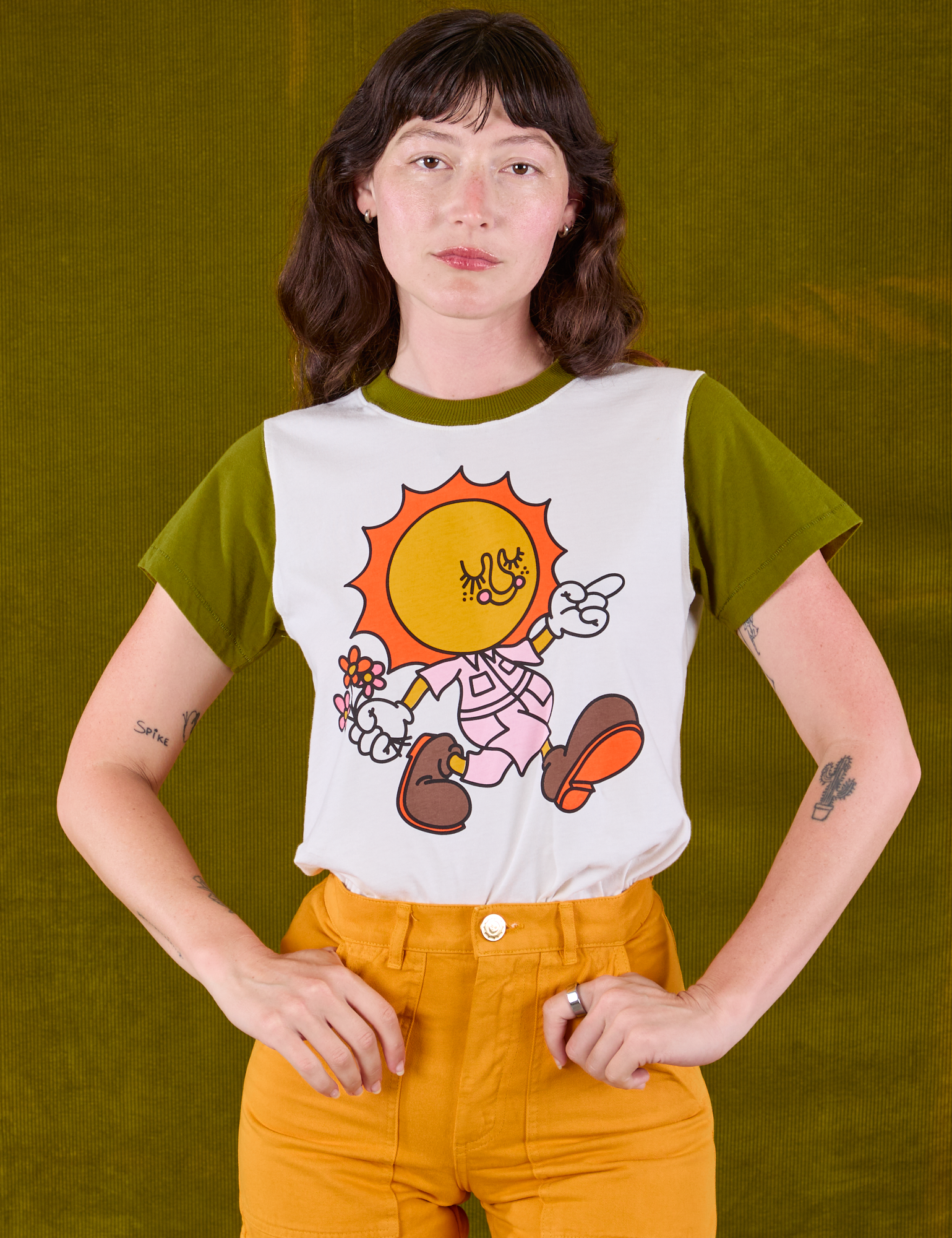 Alex is wearing Anniversary Tee in Walkin' On Sun Baby tucked into mustard yellow Work Shorts