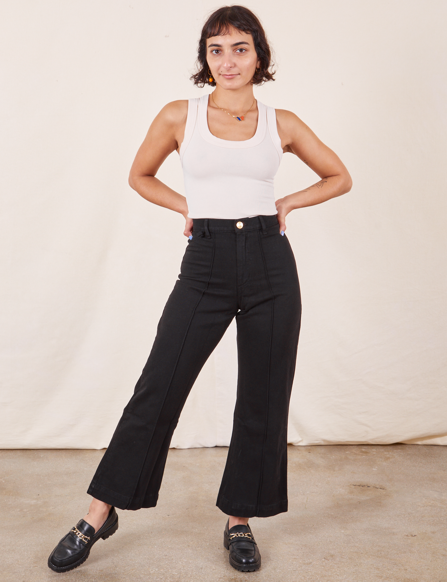 Soraya is 5'2" and wearing XXS Petite Western Pants in Basic Black paired with a Tank Top in vintage tee off-white