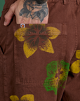 Close up of Jesse's hand in the back pocket of Floral Painted Work Pants in Brown