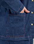 Close up of Juliet's hand in the bottom front pocket of Indigo Denim Work Jacket in Dark Wash
