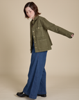 Side view of Denim Work Jacket in Surplus Green and dark wash Wide Leg Trousers on Hana