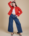Alex is wearing Denim Work Jacket in Mustang Red paired with dark wash Indigo Wide Leg Trousers