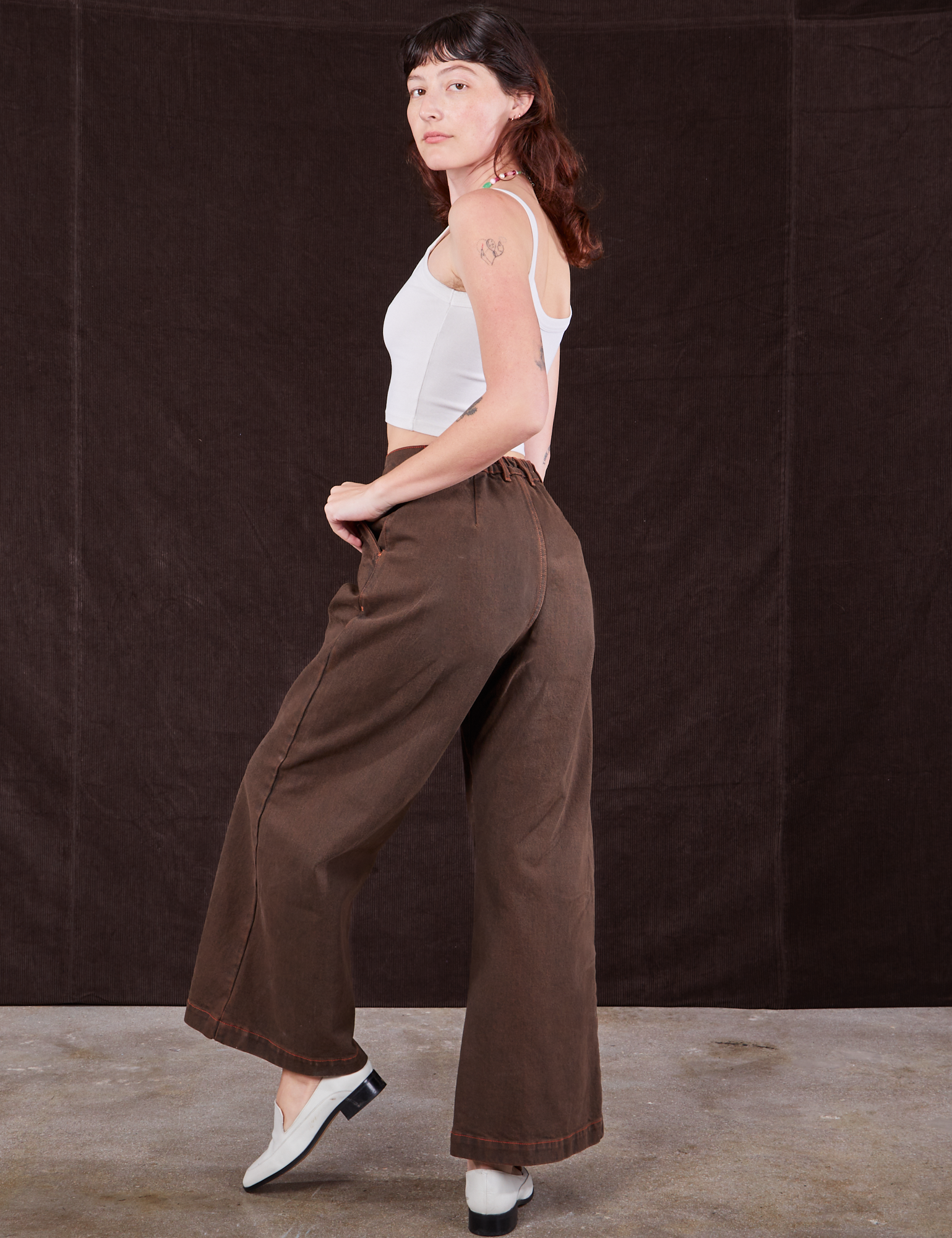 Angled back view of Overdyed Wide Leg Trousers in Brown and vintage off-white Cami on Alex