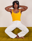 Jerrod is sitting on a olive green sofa wearing Cropped Cami in Sunshine Yellow and vintage tee off-white Western Pants