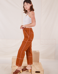Side view of Carpenter Jeans in Burnt Terracotta and Cropped Cami in vintage tee off-white on Alex