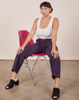 Tiara is wearing Work Pants in Nebula Purple and a Cropped Tank Top in vintage tee off-white sitting in a pink chair