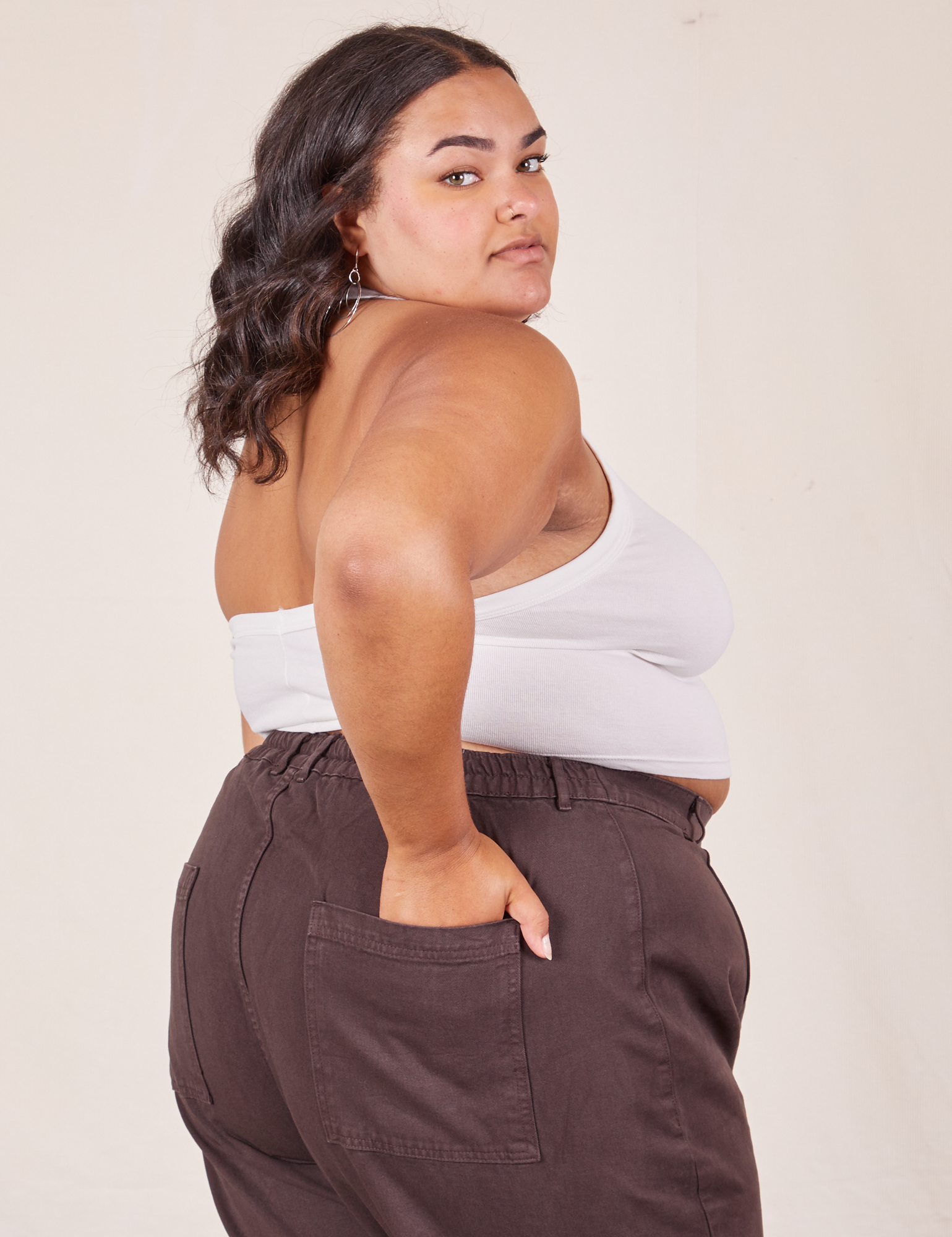 Angled back view of Halter Top in Vintage Tee Off-White and espresso brown Western Pants worn by Alicia. She has her left hand in the back pant pocket.