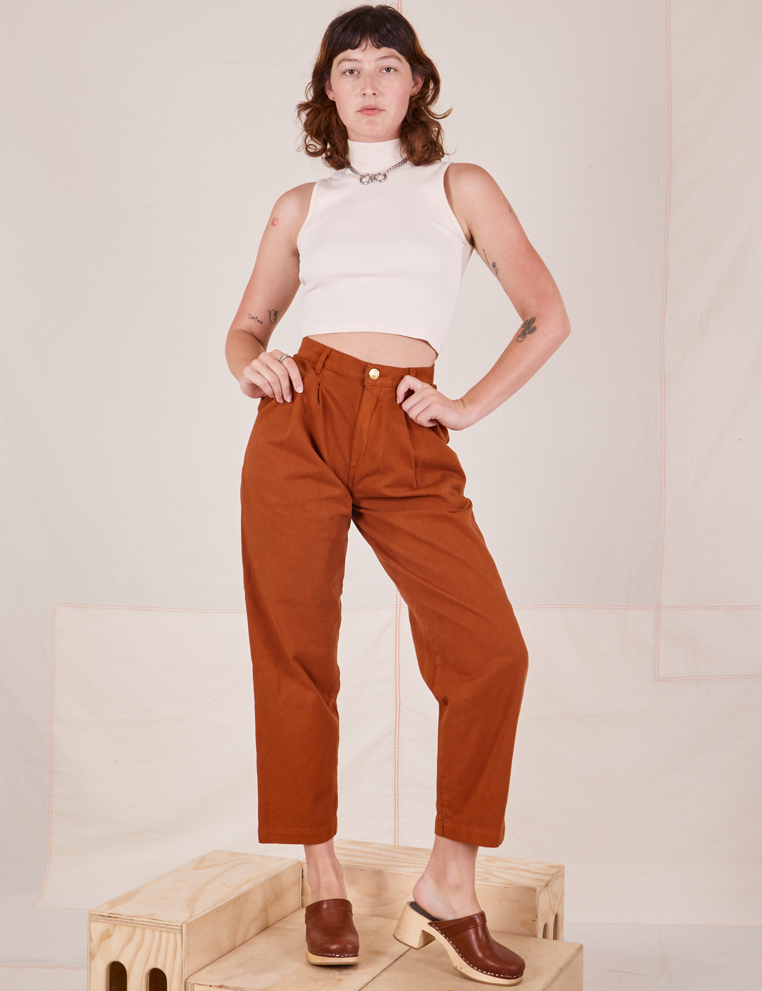 Alex is wearing Heavyweight Trousers in Burnt Terracotta and Sleeveless Turtleneck in vintage tee off-white