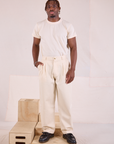 Issac is wearing Heritage Trousers in Natural  and Organic Vintage Tee in vintage tee off-white